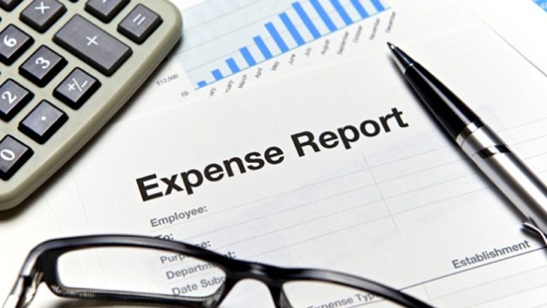 Expense report document with bar graph, calculator, pen, and eyeglasses.