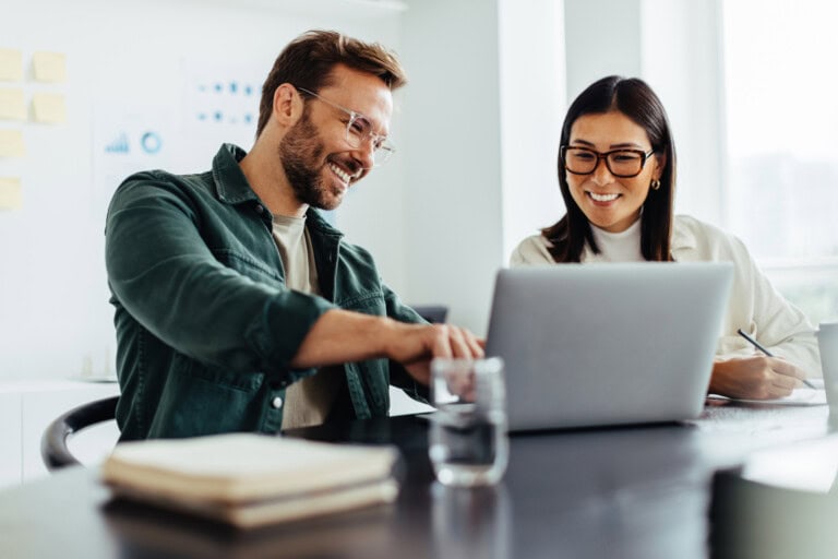 Two business people using a laptop together in an office Simplify receipt auditing with PEX’s NetSuite Integration