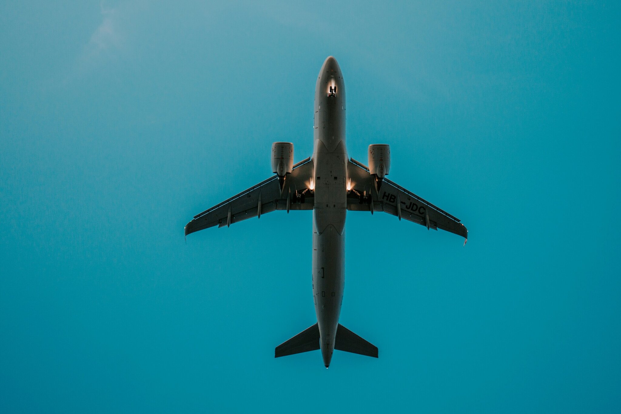 airlines A commercial airplane is seen from below flying overhead against a clear blue sky.