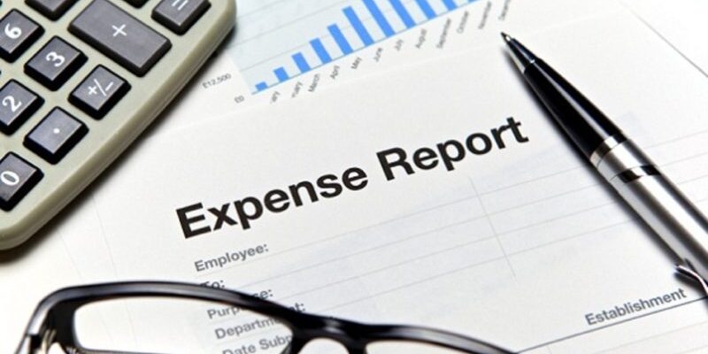 Expense report document with bar graph, calculator, pen, and eyeglasses.