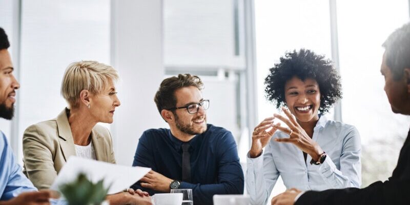 Five people sit around a table in a brightly lit office, engaged in conversation about how automation is transforming B2B bill pay