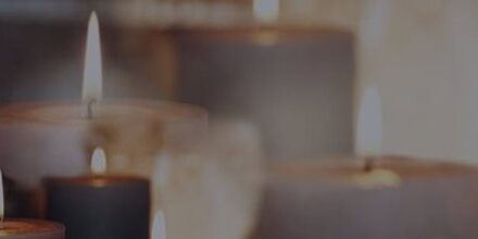 Several lit candles with soft, glowing flames arranged in a row, creating a warm and calming atmosphere.