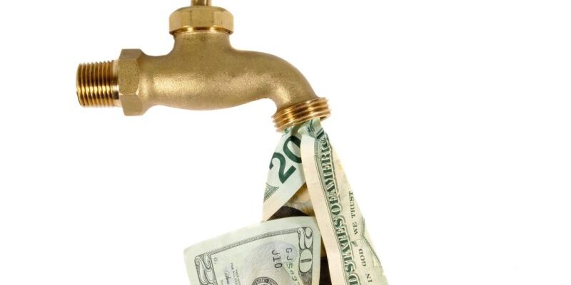 A brass faucet is releasing a flow of U.S. dollar bills instead of water.