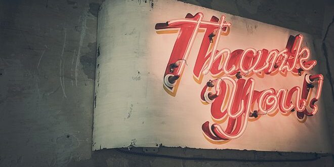A vintage neon sign mounted on a worn wall displays the words “Thank You” in red script.