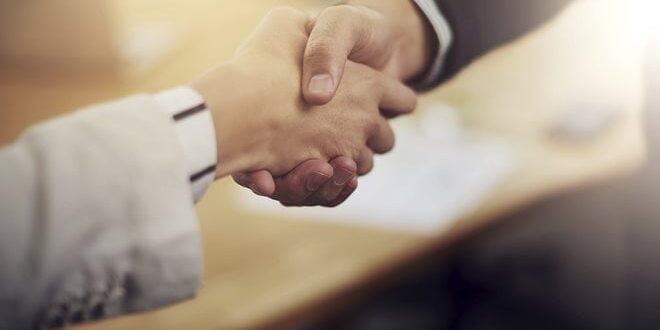 Two people shaking hands, with a blurred background and soft lighting.