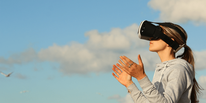 A person wearing a VR headset stands outdoors, looking up with clouds and birds in the background.