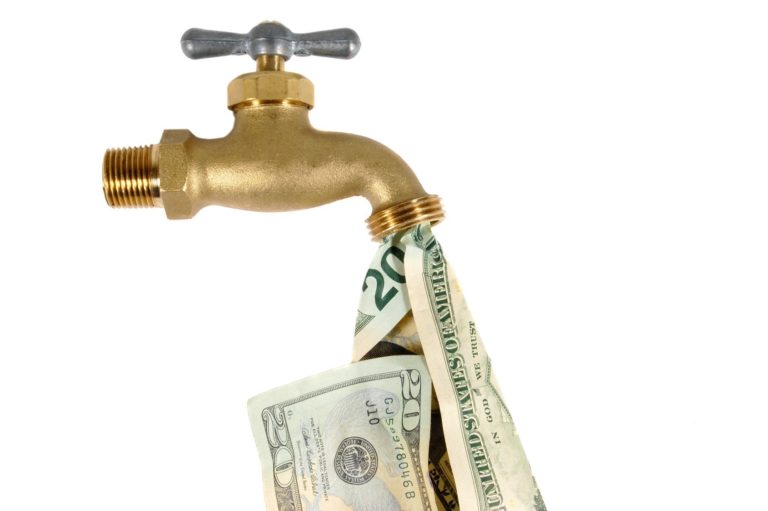 A brass faucet is releasing a flow of U.S. dollar bills instead of water.