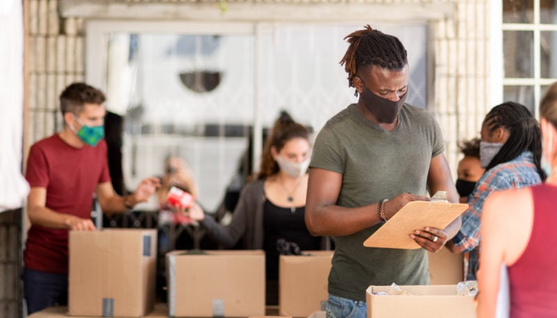 Young African man wearing a protective face mask taking inventory of food donations at a community outreach center