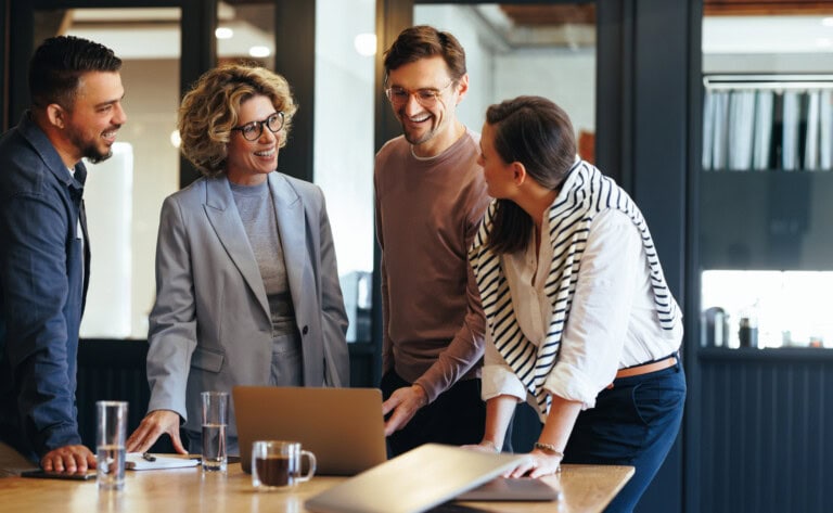 Four people gather around a table, engaged in conversation about the latest expense reporting software and the increased purchasing power to grow their business.