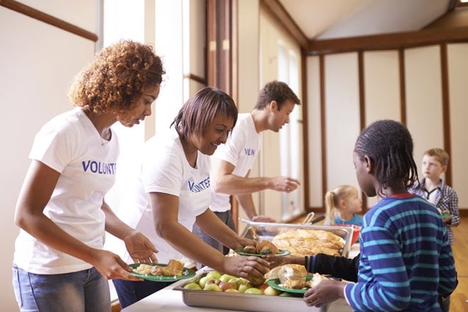 nonprofitmoney.jpg Volunteers distribute meals to children in a dining area.