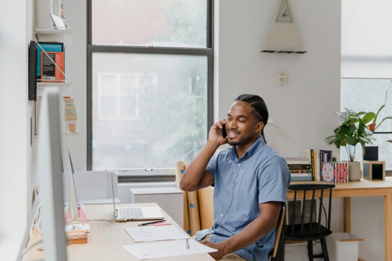 pexels-rdne-10376033 A person sits at a desk, talking on the phone while using spend management software on a laptop.