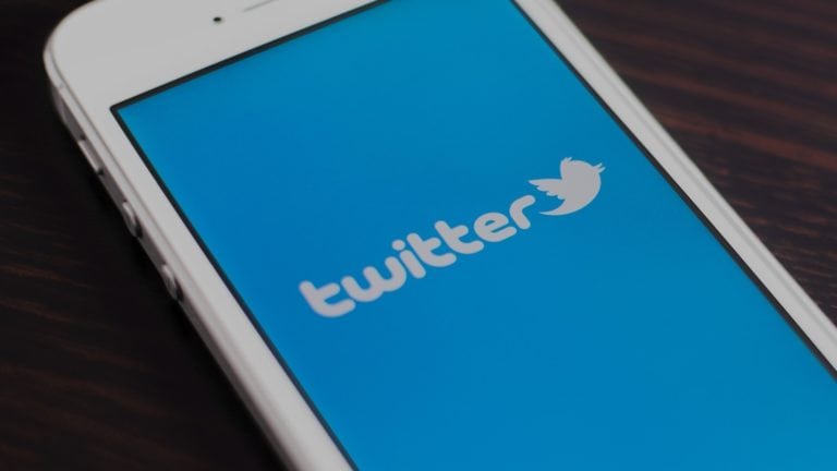 Smartphone displaying the Twitter logo on a blue screen.